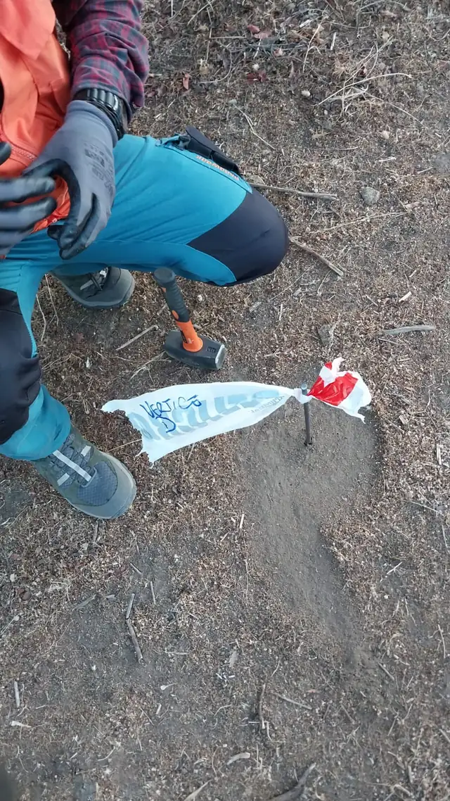 Vértice de deslinde estacado con fierro de acero y banderín rotulado Vértice B, junto a un martillo en el suelo
